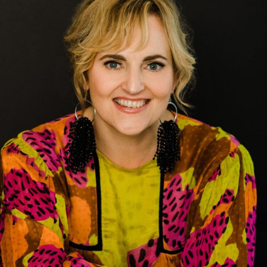 A smiling woman in a colorful shirt.