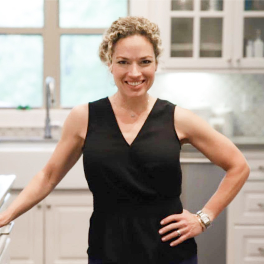 A woman in a black top standing in a kitchen.