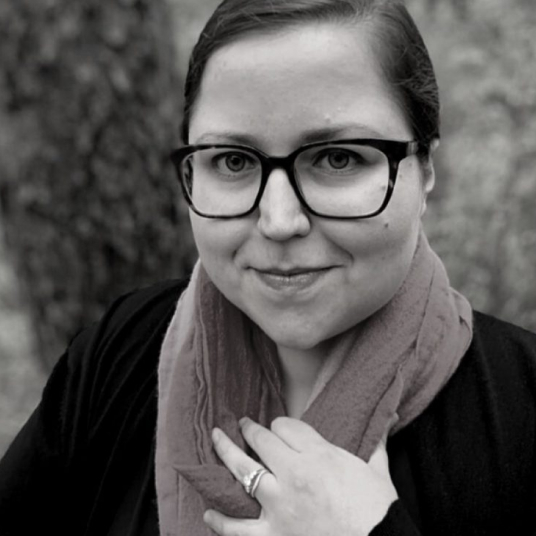 A black and white photo of a woman wearing glasses and a scarf.